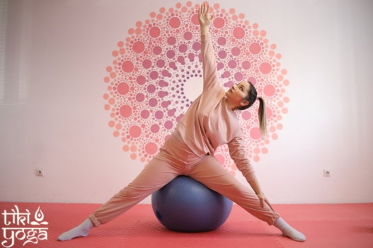 devojka na lopti izvodi vežbe joge